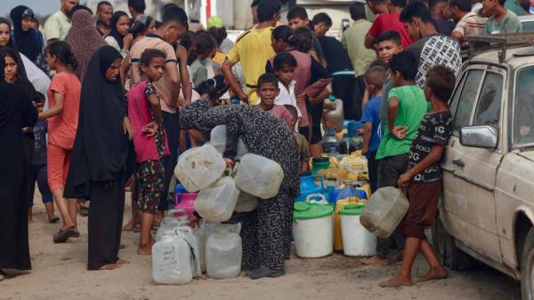 فلسطينيون يصطفون للحصول على مياه الشرب في ظل الحر الشديد في منطقة المواصي (أ ف ب)