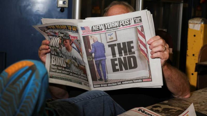 يقرأ صحيفة نيويورك تايمز التي تحمل عنوان «النهاية» مع صورة بايدن مغادراً (رويترز)
